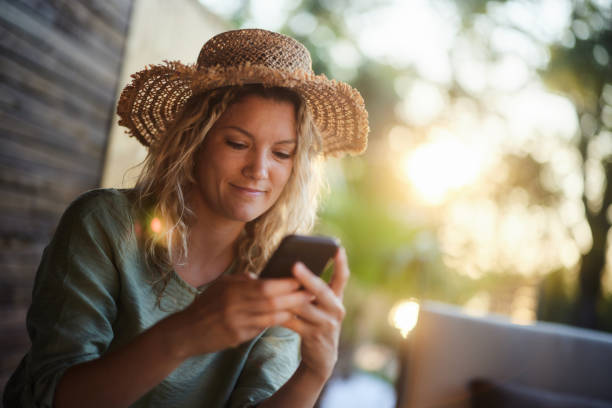 istock Smiling woman text messaging on cell phone on a patio. 1675574572