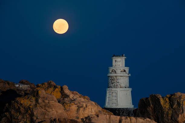 istock Big super moon over lighthouse in the sea 1675592150