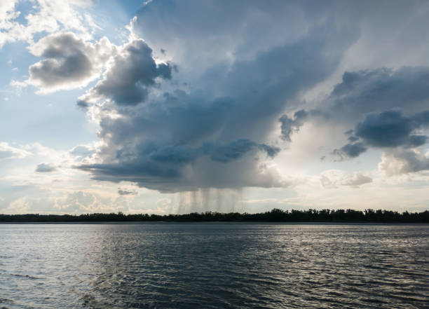 istock The sun shines behind rain clouds over the river and the forest 1675602726