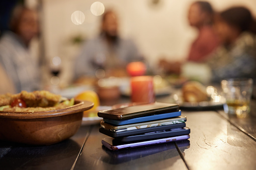 Close up of pile of cell phones confiscated during a meal at dining table.