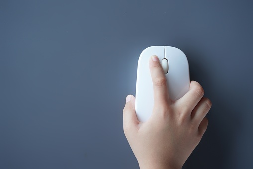 Top view image of small kid's hand using computer mouse. Copy space for text. Technology concept