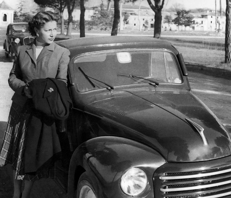 Young woman and vintage car Fiat 500 Topolino in a street. 1940.