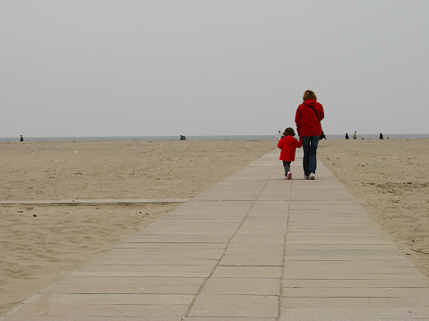 Mother and daughter go to the beach to go see the Adriatic sea in autumn in Rimini, Italy