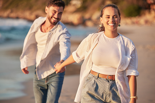 Happy couple, beach and travel while holding hands, laughing and having fun on Portugal summer vacation or holiday traveling to seaside. Smile of man and woman on honeymoon sharing love and adventure