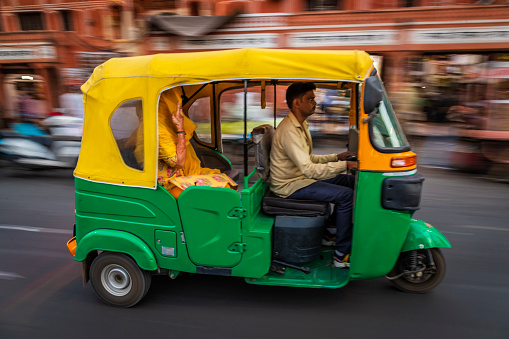 Indian man drives auto rickshaw (tuk-tuk) on streets of Rajasthan, India.