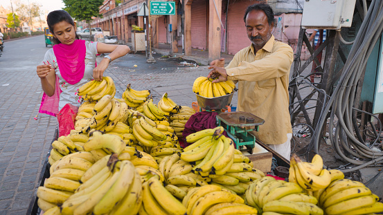 Young Indian woman buying bananas on the streets of The Pink City in Jaipur, Rajasthan, India. Jaipur is known as the Pink City, because of the color of the stone exclusively used for the construction of all the structures.