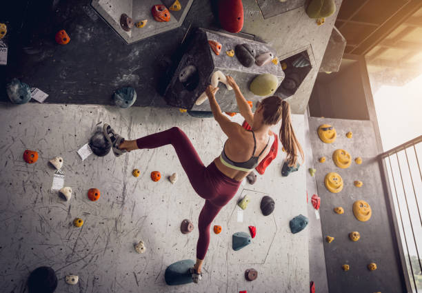 istock A strong female climber climbs an artificial wall with colorful grips and ropes. 1675700118