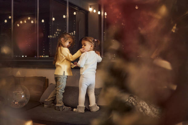 Children are having fun during New Year's Eve. They are decorating Christmas Tree, giving presents, playing.