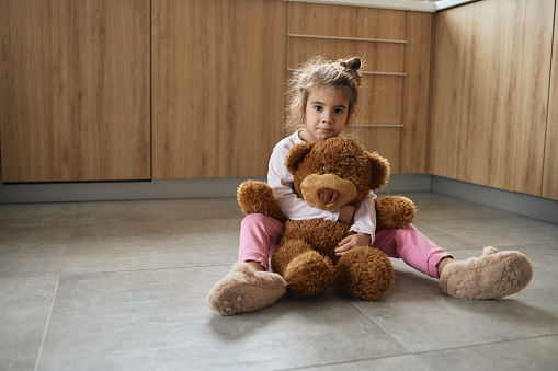 Small girl with chickenpox hugging teddy bear.