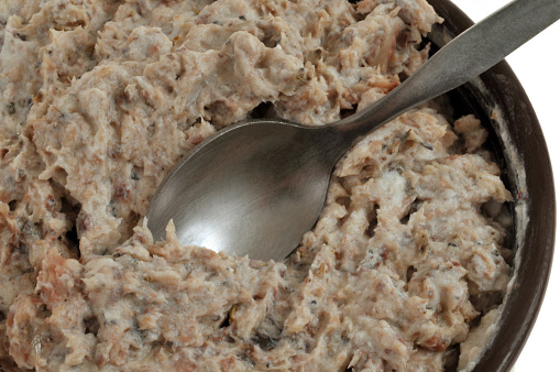 Ramekin of homemade tuna rillettes with a spoon close-up