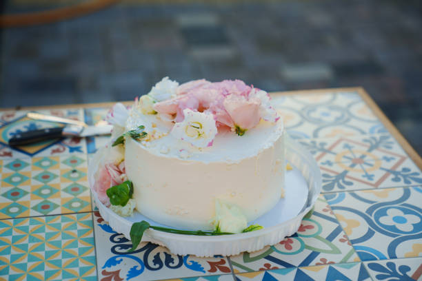 istock Classic white cake decorated with pink and white fresh flowers. 1675754246