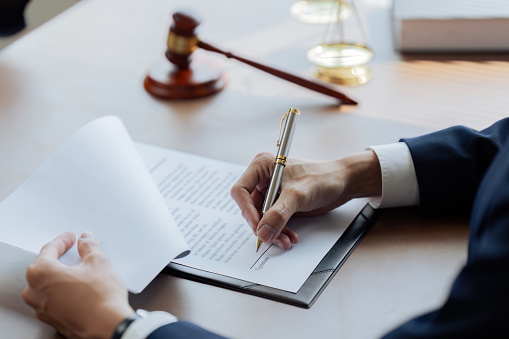 Lawyers or judges sign documents in accordance with legal and fair terms of agreement.