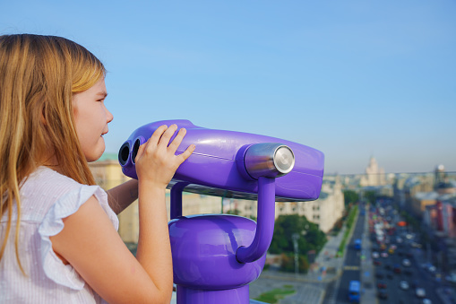 a teenage girl looks into the Binoscope from the observation deck at a height. A popular entertainment for tourists.