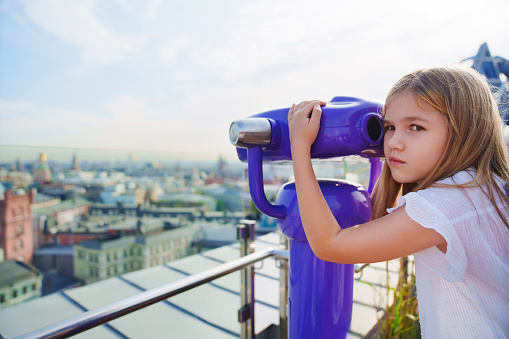 a teenage girl looks into the Binoscope from the observation deck at a height. A popular entertainment for tourists.