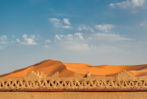 Detail of building in front of sand dune in Sahara desert. Morocco, Africa.