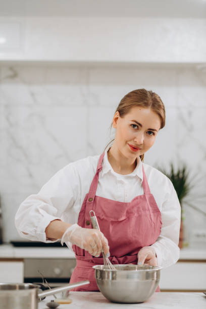 istock Happy young cook girl wearing apron, using mobile phone in home kitchen while baking pie, pizza, pastry, taking photo of raw bakery food for blog, chatting, making call 1675776056