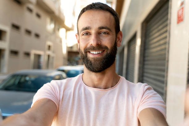 istock Hispanic influencer recording video using modern technology outdoors. Smiling tourist taking selfie 1675780557