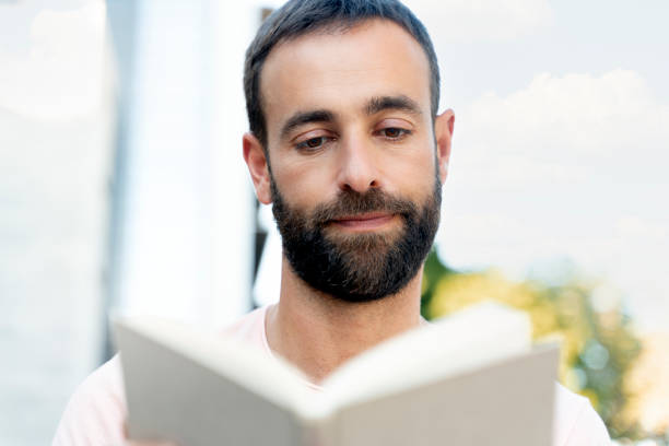 istock Handsome hispanic man reading book outdoors. Pensive student studying, education concept 1675780693