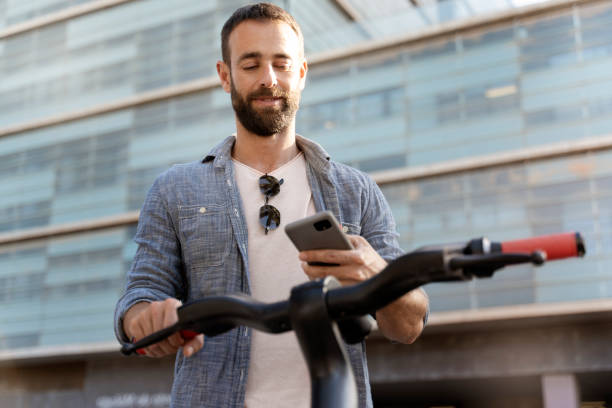 istock Handsome latin man using mobile app scanning qr code for rental electric scooter 1675780735