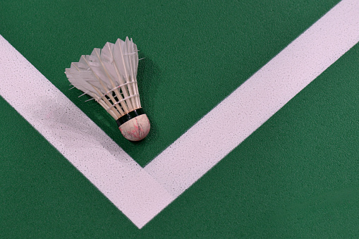 White shuttlecock for playing badminton on a green indoor badminton court