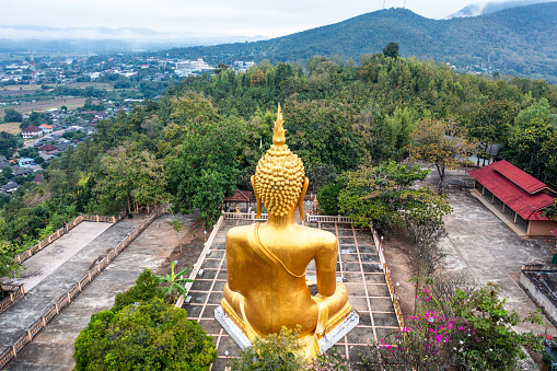 Local man wearing sarong walking at a Buddha statue in Champasak Province, Laos