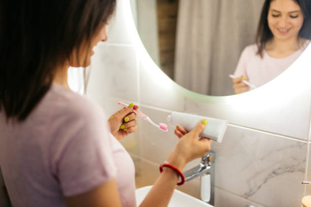 istock Young Woman Putting Toothpaste On A Toothbrush 1675796145