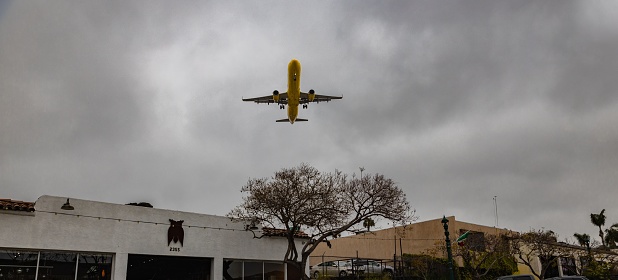 San Diego, United States – April 12, 2023: A commercial airliner flying low over buildings before landing in San Diego, California.