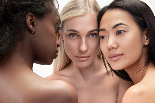 Multiracial beauty. Three young asian, caucasian and african tender woman standing against white background. Concept of multi ethnic beauty, natural, spa, cosmetology, wellness, ad