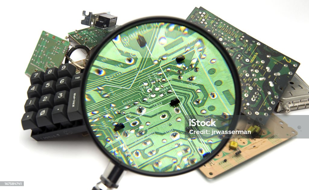 Closeup on Digtial Garbage Concept photo showing digital computer parts discarded in garbage pile examined with maginfying glass Circuit Board Stock Photo