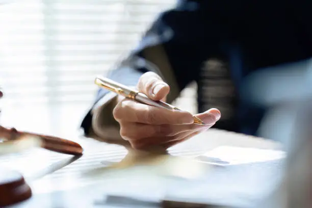 Photo of Close up lawyer hands holding pen, signing in white paper form or application to confirm and deal contract agreement