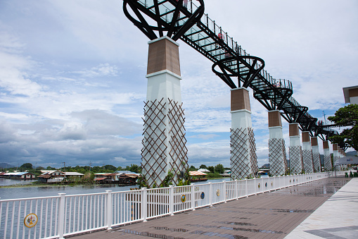 Skywalk bridge stretching parallel to banks of Khwae Yai or Si Sawat river for thai people foreign travelers travel visit and walking on clear glass bridge on August 30, 2023 in Kanchanaburi, Thailand