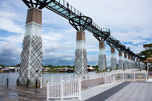 Skywalk bridge stretching parallel to banks of Khwae Yai or Si Sawat river for thai people foreign travelers travel visit and walking on clear glass bridge on August 30, 2023 in Kanchanaburi, Thailand