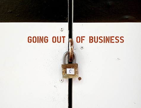 Commercial shop house pink rolling door closed with padlock -  text inscription GOING OUT OF BUSINESS , small business retailer shut down permanently out of business due to pandemic or economy crisis