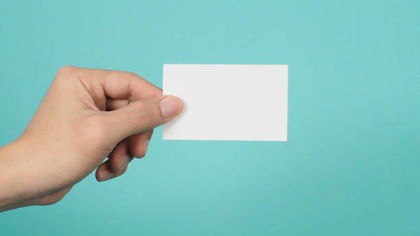 istock Hand holding white blank card isolated on mint green or Tiffany Blue background. 1675861490