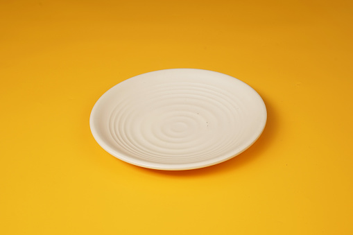 White plate isolated on yellow background
