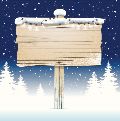 Old wooden sign in the snow with fairy lights