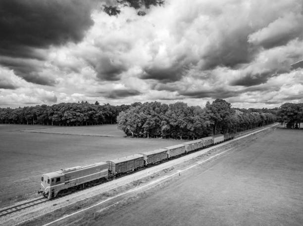 Old diesel freight train in the countryside seen from above. The antique diesel locomotive is pulling freight cars over a railroad track through the woods and fields.