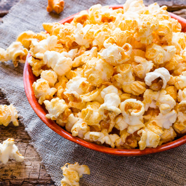 istock Popcorn in a bowl and scattered on a table close-up 1675914542
