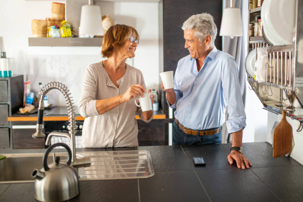istock older couple smiling in kitchen with cup of coffee 1675915137