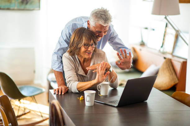 istock older happy couple at table looking at laptop video call 1675915172