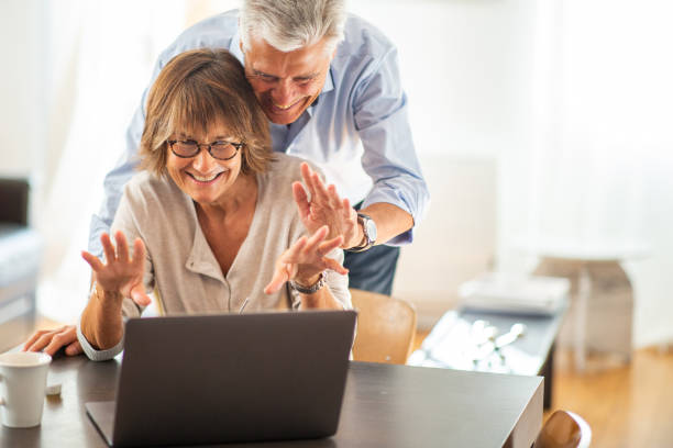 happy older couple looking at laptop screen during video call