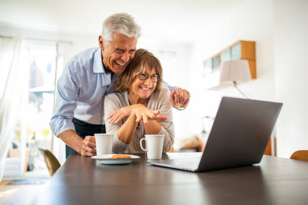 istock happy couple sitting at table looking at laptop screen video call 1675915178