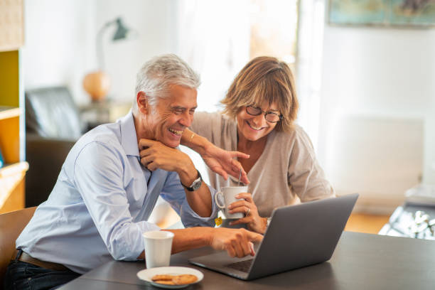 istock smiling older couple sitting at table looking at laptop 1675915186
