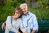 happy older couple sitting on park bench