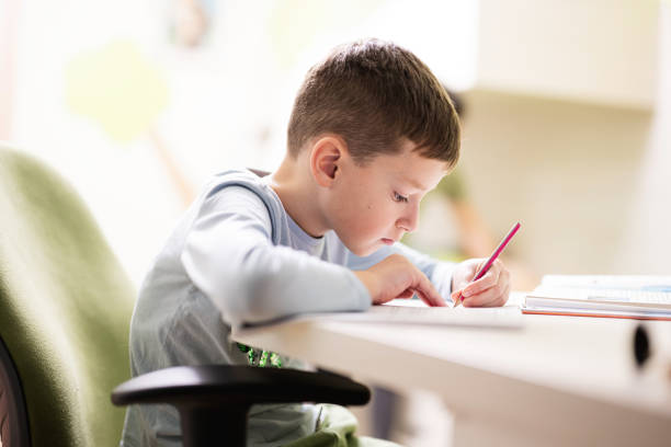 istock Kid boy studying at home and doing school homework, distance learning education , sitting at table. 1675916309