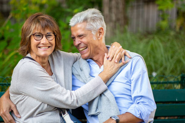 istock older loving couple sitting outside on park bench 1675916313