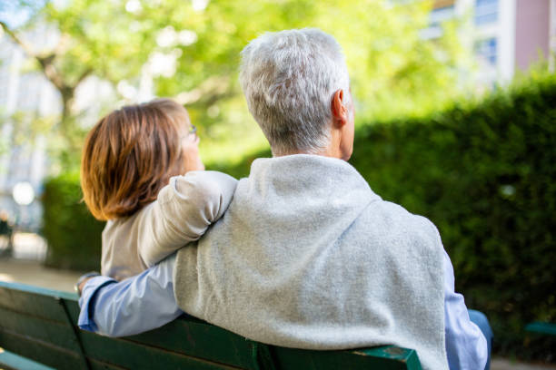 istock back of older couple sitting on park bench 1675916336