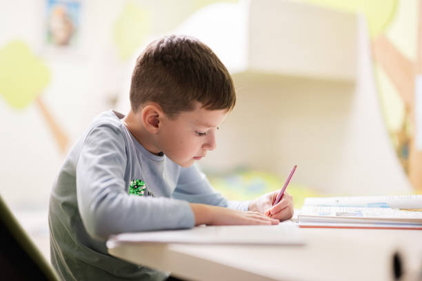 istock Kid boy studying at home and doing school homework, distance learning education , sitting at table. 1675916615