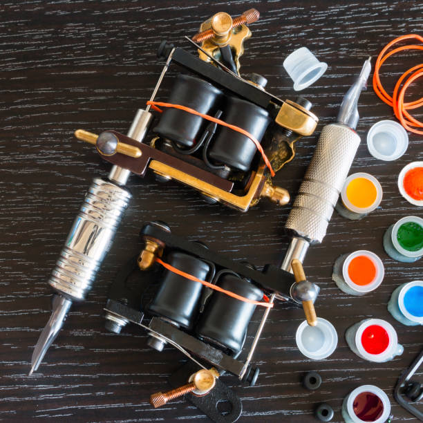 Two tattoo machines and ink on a black background with space for text