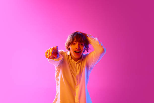 istock Young excited guy pointing with finger, expressing emotions against pink studio background in neon lights. Sales 1675919157